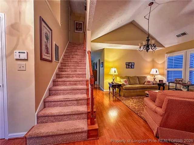 a living room with furniture and a dining table with wooden floor