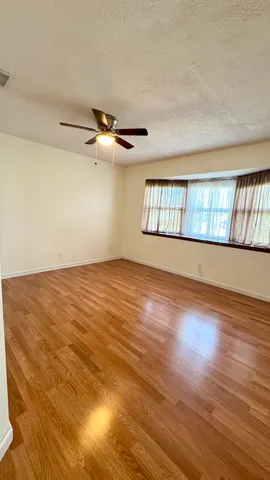 a view of an empty room with window and wooden floor