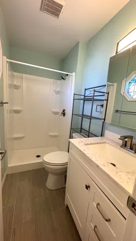 a bathroom with a sink a toilet and shower