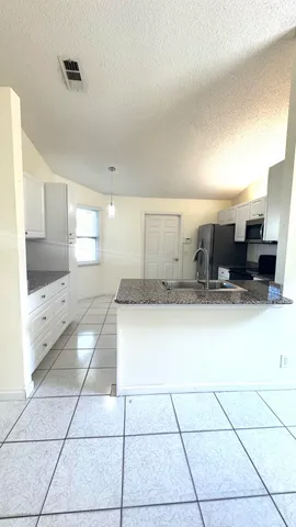 a large white kitchen with a sink and a large window