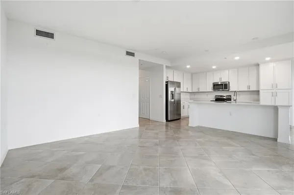 a large kitchen with kitchen island a refrigerator a stove a sink a oven and white cabinets