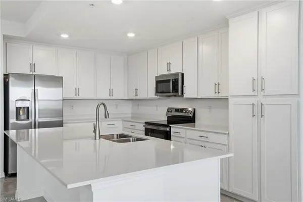 a kitchen with white cabinets appliances and sink