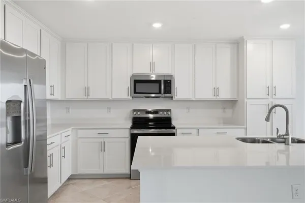 a large white kitchen with granite countertop a sink and a white stove next to a large window