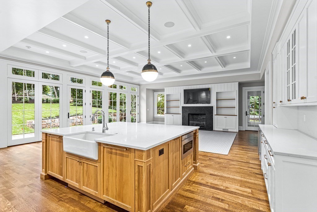 8 Lowell Road Wellesley, MA 02481 - Photo 7 of 16 a large kitchen with kitchen island a stove a sink a dining table and chairs with wooden floor