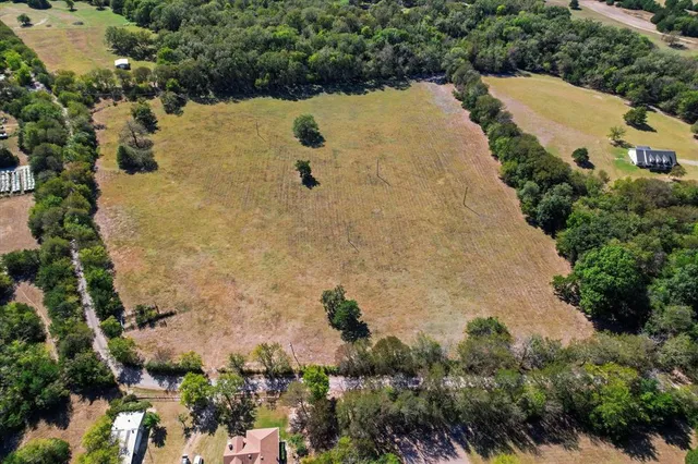 an aerial view of a house with a yard and trees all around