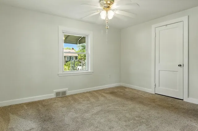 an empty room with windows and fan