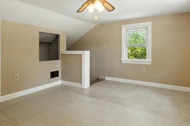 an empty room with a window and a chandelier fan