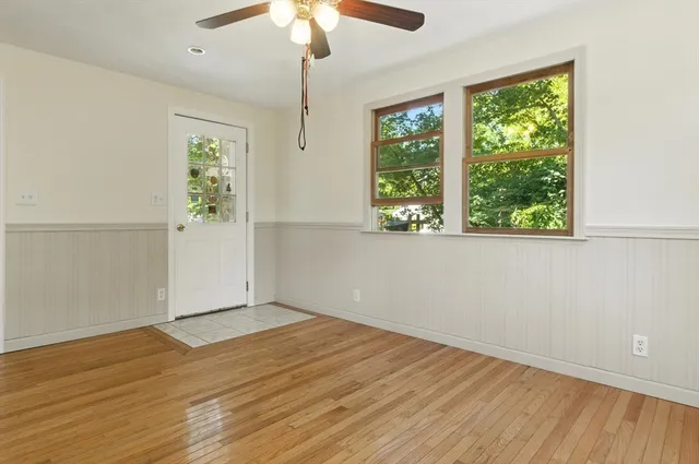 an empty room with wooden floor chandelier fan and windows