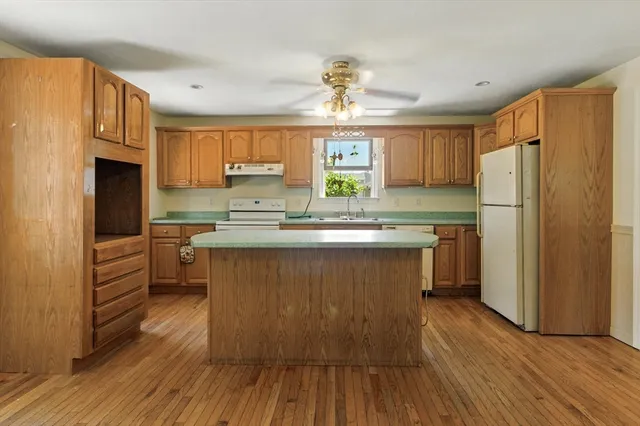 a kitchen with kitchen island granite countertop wooden floors appliances and cabinets