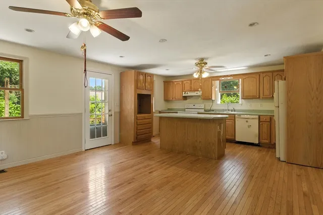 a kitchen with stainless steel appliances a sink cabinets wooden floor and a window