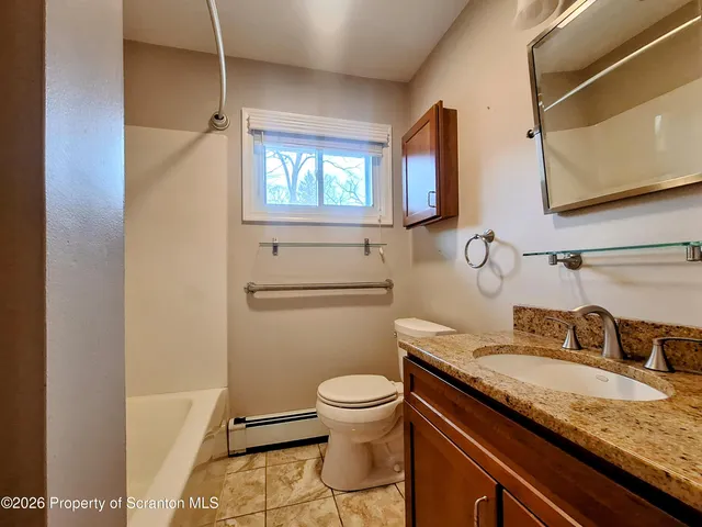 a bathroom with a granite countertop sink toilet and mirror