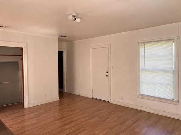 a view of an empty room with wooden floor and closet
