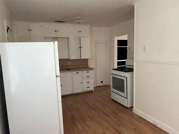 a kitchen with granite countertop white cabinets and white appliances