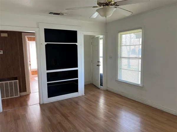 an empty room with wooden floor closet and windows