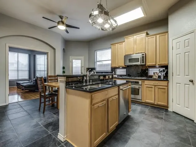 a kitchen with kitchen island granite countertop a sink cabinets and stainless steel appliances