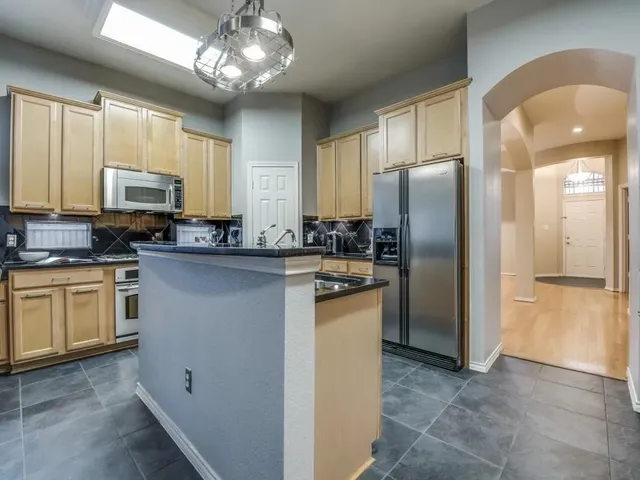 a kitchen with stainless steel appliances granite countertop a refrigerator a stove a sink and a microwave