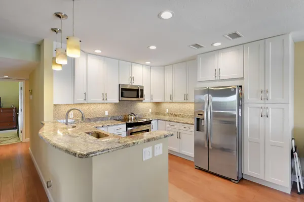 a kitchen with kitchen island granite countertop stainless steel appliances cabinets a sink and a counter top space