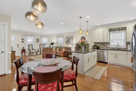 a kitchen with stainless steel appliances granite countertop a stove top oven a refrigerator a sink dishwasher a dining table and chairs with wooden floor