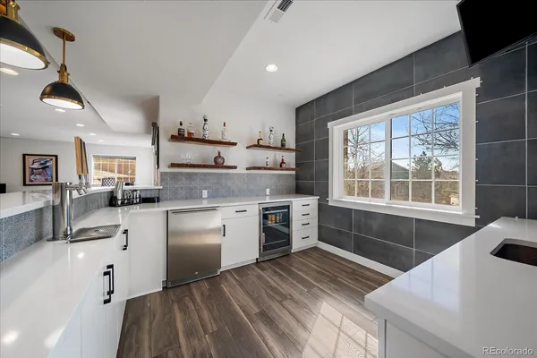 a kitchen with granite countertop a stove a sink and white cabinets with wooden floor