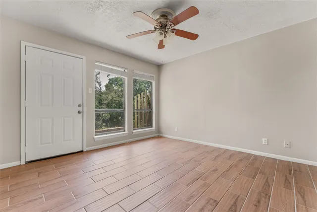 a view of room with window ceiling fan and wooden floor