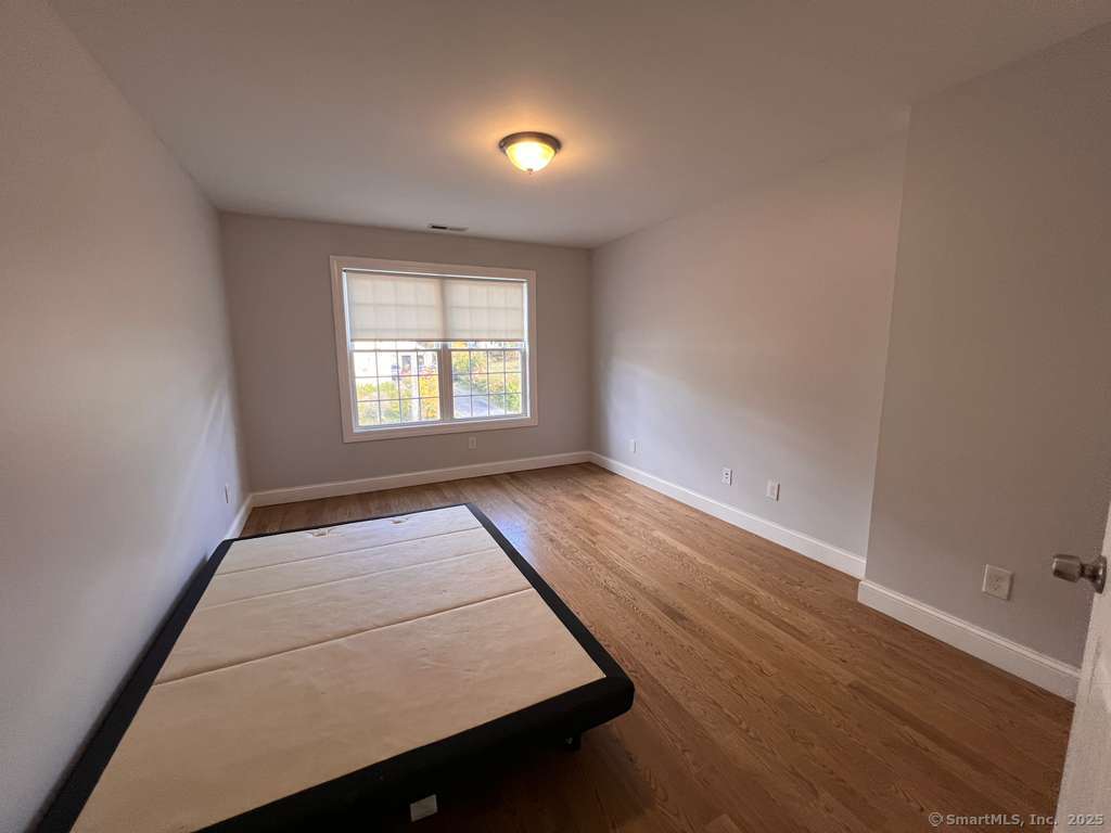 793 Pond Street Bridgeport, CT 06606 - Photo 22 of 28 an empty room with wooden floor and windows