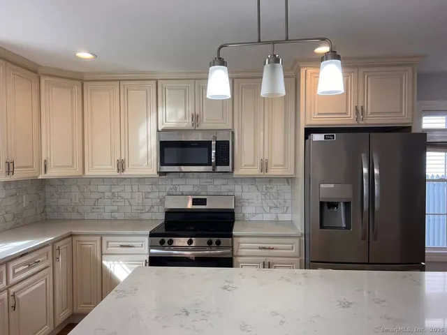 a kitchen with stainless steel appliances kitchen island granite countertop a refrigerator a stove a sink and a microwave