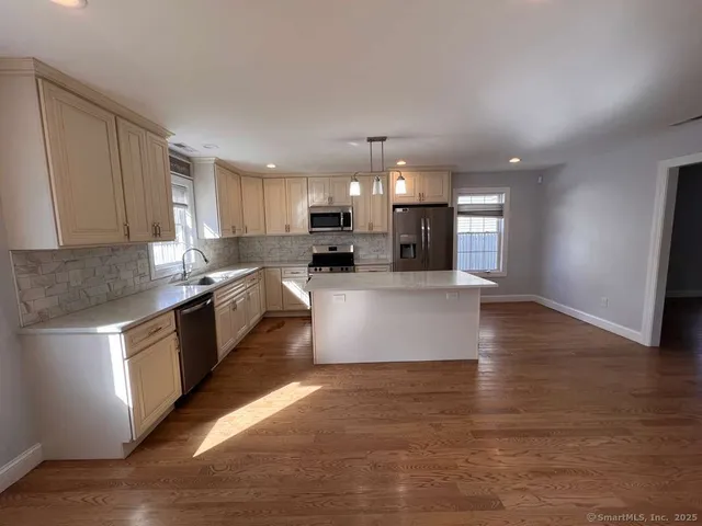 a large kitchen with stainless steel appliances granite countertop a lot of counter space and wooden floor