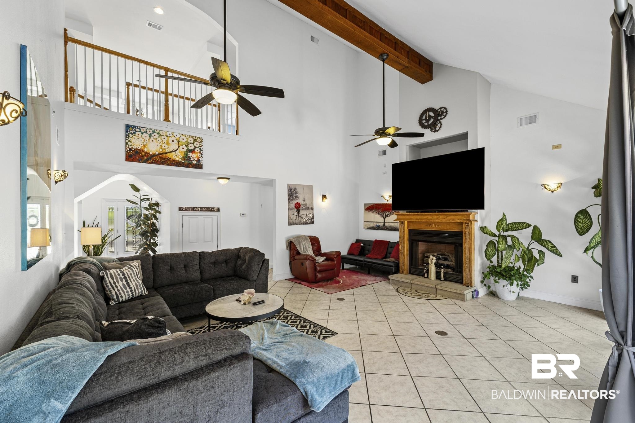 32875 Faircloth Road Lillian, AL 36549 - Photo 30 of 85 Living area with light tile patterned floors, a ceiling fan, a fireplace with raised hearth, lofted ceiling, and arched walkways