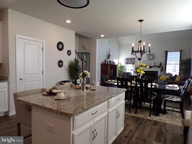 a kitchen with granite countertop a dining table chairs and white cabinets