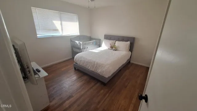 a bedroom with a bed window and wooden floor