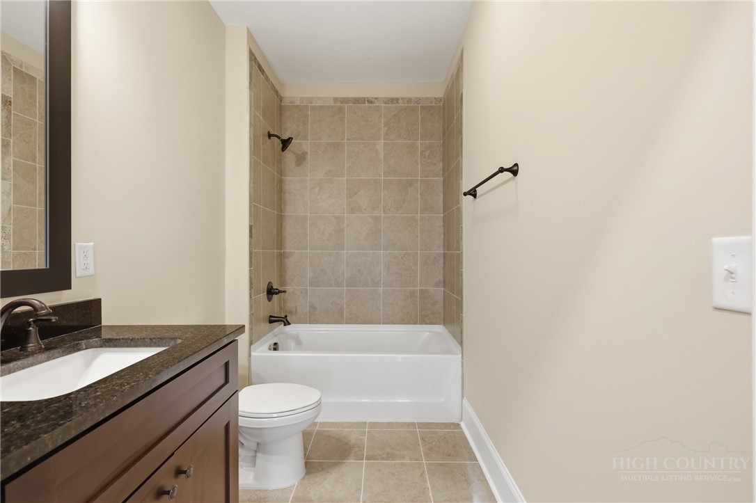 155 Gateway Drive, Unit 102 Boone, NC 28607 - Photo 13 of 43 a bathroom with a granite countertop bathtub shower sink vanity and toilet