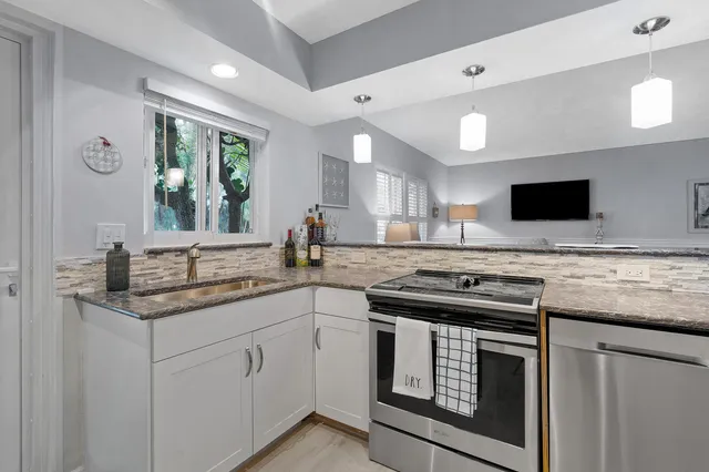 a kitchen with granite countertop stainless steel appliances white cabinets and a sink