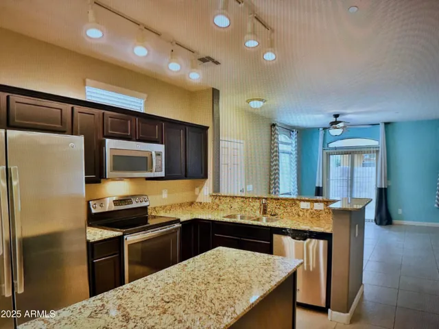 a kitchen with granite countertop a stove refrigerator and microwave