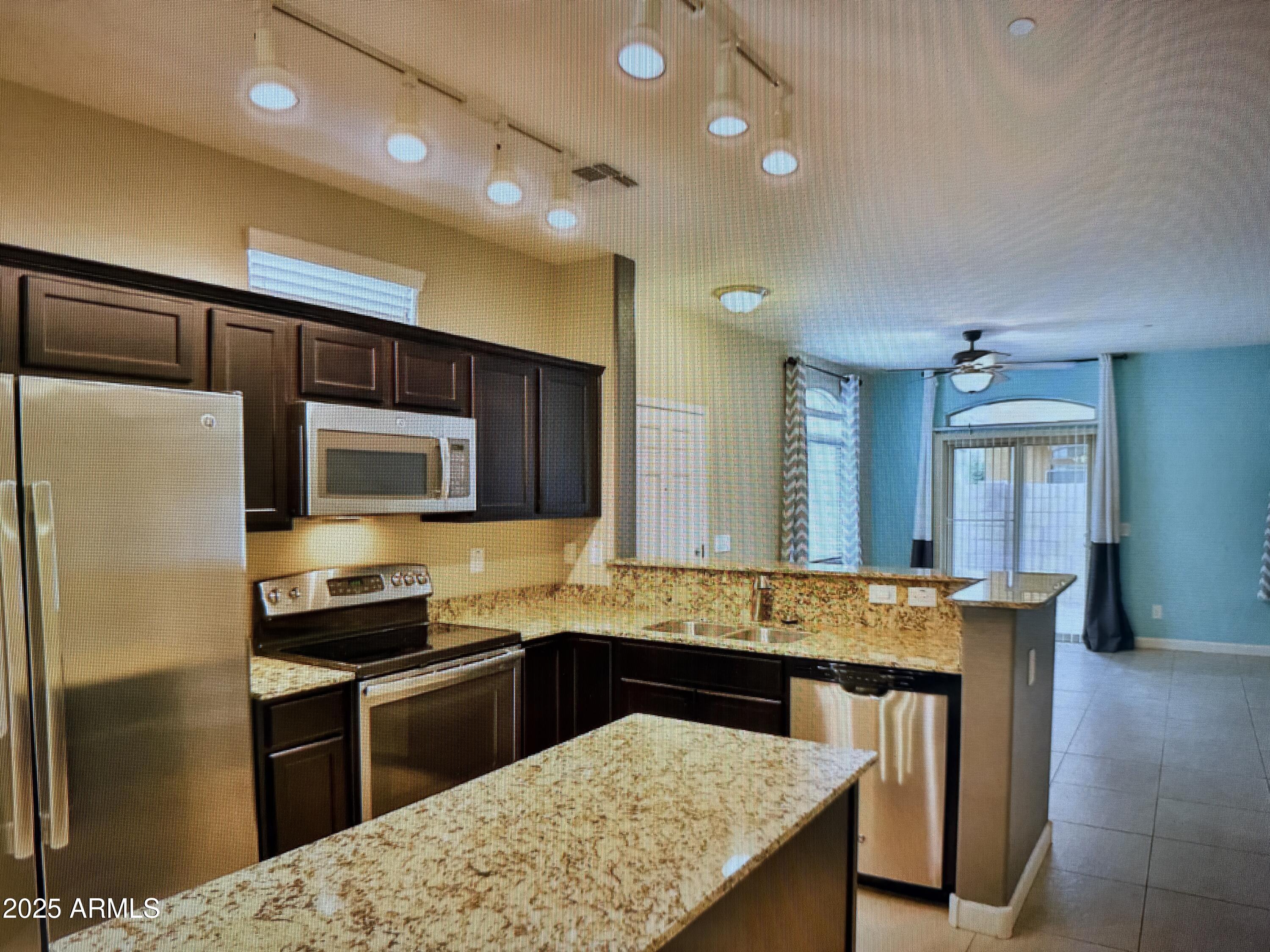 2150 West Alameda Road, Unit 1259 Phoenix, AZ 85085 - Photo 5 of 18 a kitchen with granite countertop a stove refrigerator and microwave