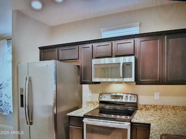 a kitchen with stainless steel appliances granite countertop a refrigerator and a stove top oven