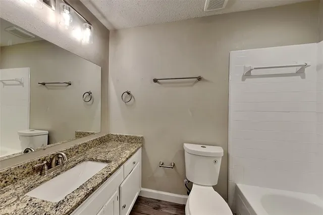 a bathroom with a granite countertop sink a toilet and shower