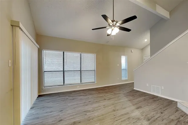 a view of an empty room with window and wooden floor