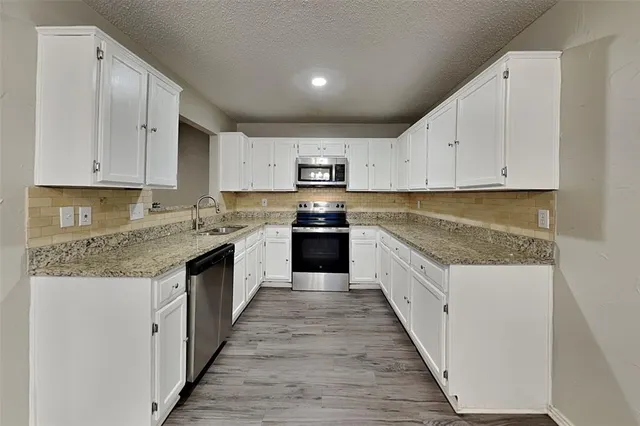 a large kitchen with granite countertop a stove top oven a sink and dishwasher with wooden floor