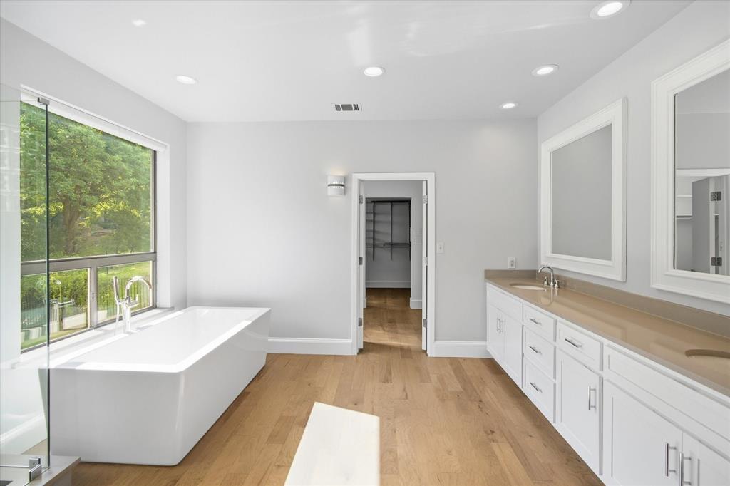 3606 Labrador Grapevine, TX 76051 - Photo 26 of 38 Freestanding soaking tub with a full-height window, dual vanity with undermount sinks, wood-finish flooring, and recessed lighting
