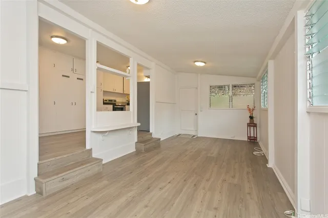 a view of a hallway with wooden floor and a kitchen