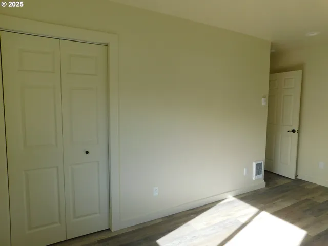 a view of a room with wooden floor and a white wall