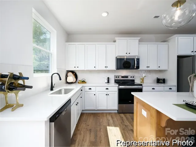 a kitchen with stainless steel appliances a sink a stove a refrigerator cabinets and a window