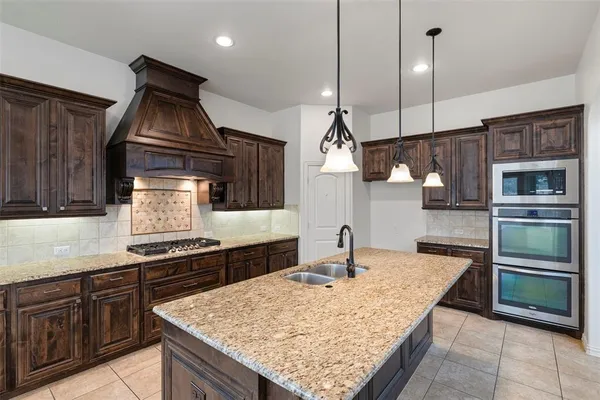 a kitchen with stainless steel appliances granite countertop a stove a sink and a refrigerator