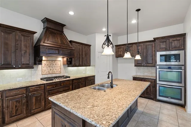 a kitchen with stainless steel appliances granite countertop a stove a sink and a refrigerator