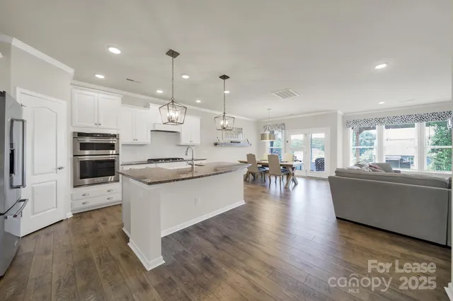 a living room with stainless steel appliances kitchen island hardwood floor sink stove and wooden floor