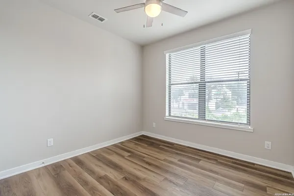a view of an empty room with wooden floor and a window