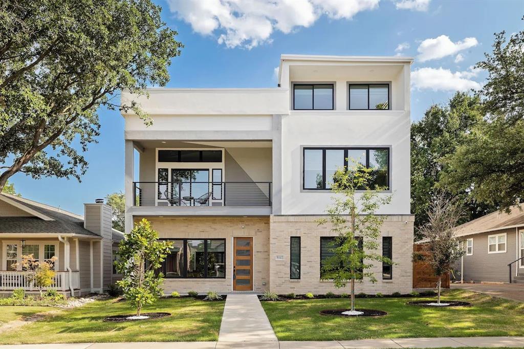 Contemporary home with stucco siding, brick siding, a balcony, and a front yard