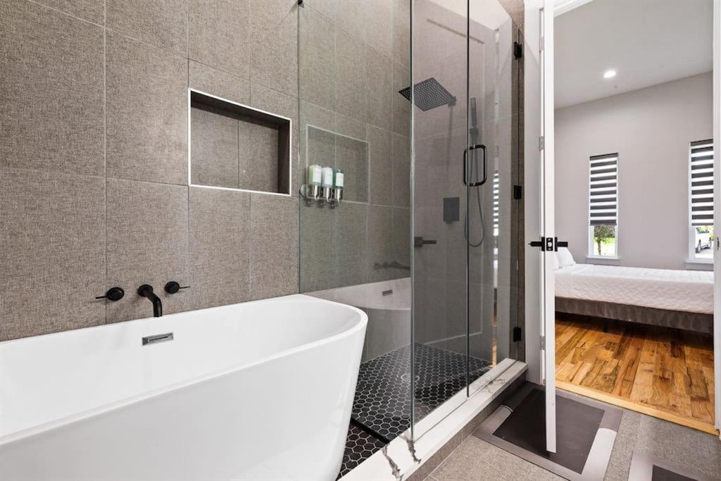 5942 Prospect Avenue Dallas, TX 75206 - Photo 12 of 25 Bathroom with a shower stall, a freestanding tub, tile walls, connected bathroom, and recessed lighting