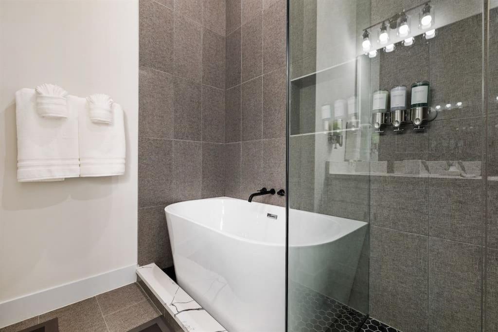 5942 Prospect Avenue Dallas, TX 75206 - Photo 13 of 25 Bathroom featuring tile walls, a freestanding tub, a walk in shower, and tile patterned floors