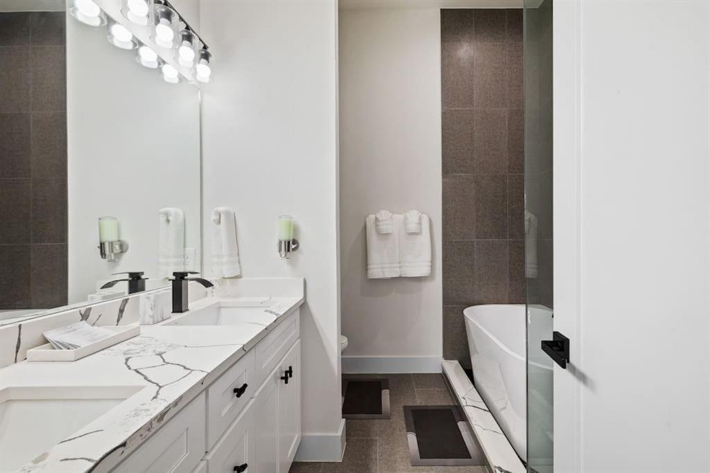 5942 Prospect Avenue Dallas, TX 75206 - Photo 6 of 25 Full bathroom with a soaking tub, double vanity, and dark tile patterned flooring